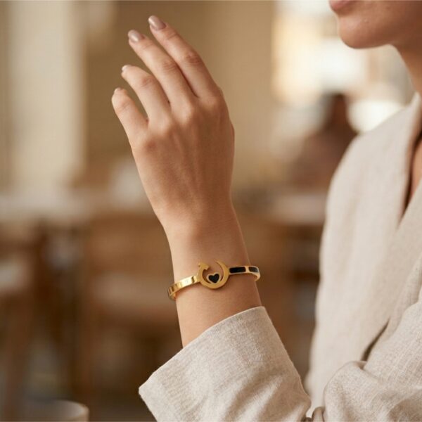 Woman's minimal gold bracelet with black heart design, elegant everyday jewellery look